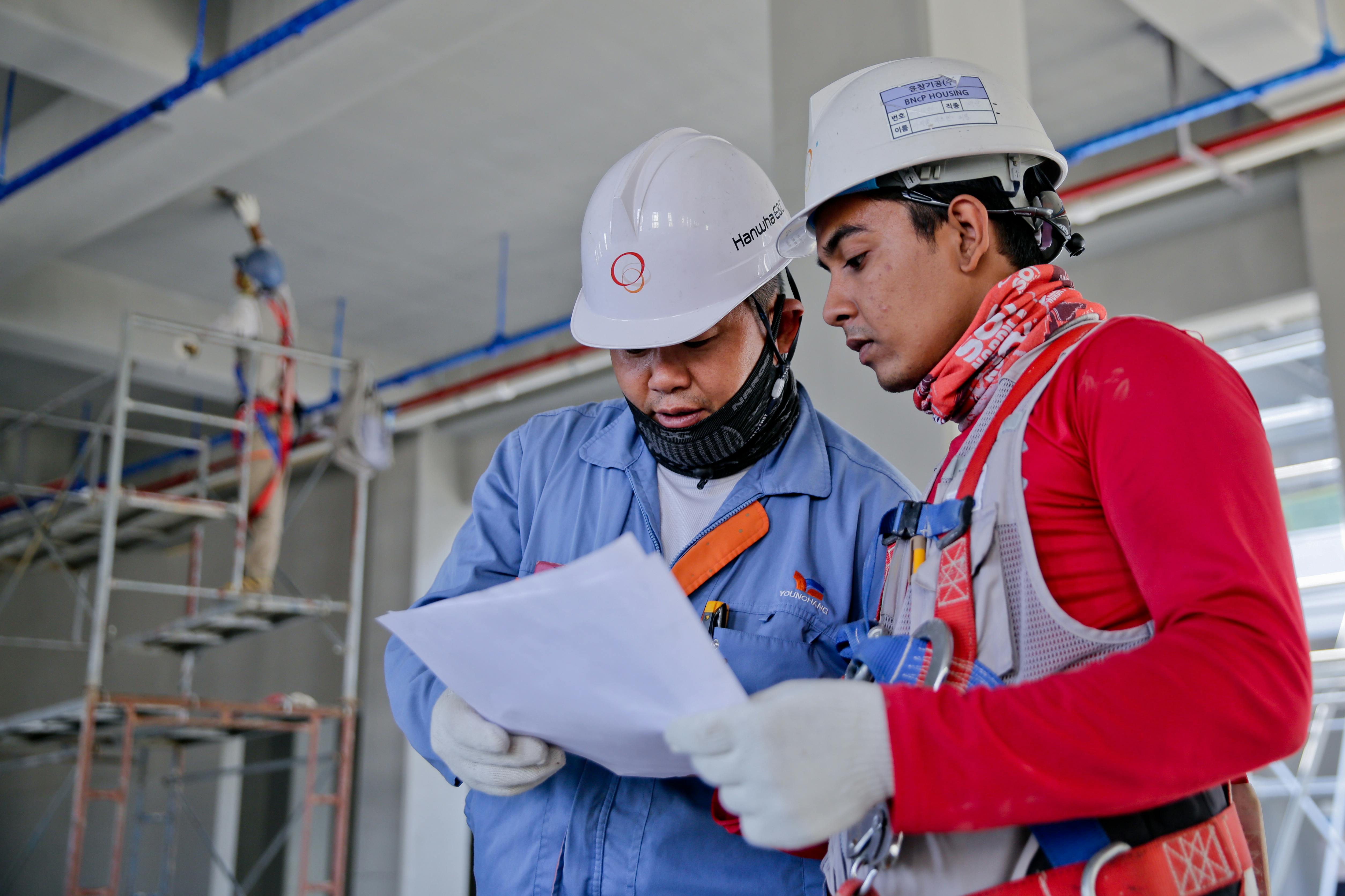 pexels photo 1216589 1216589 1 Two engineers in safety helmets reviewing construction plans at a worksite.
